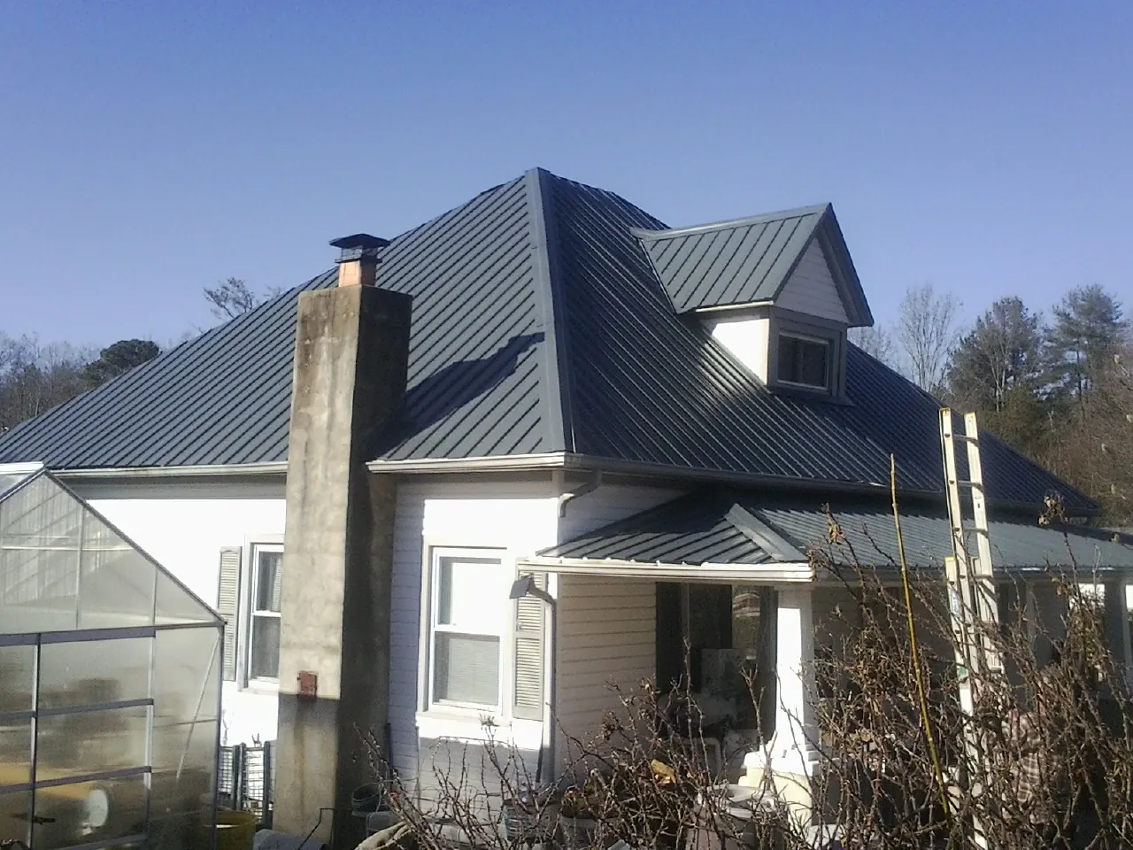 Dark blue standing seam metal roof on a white farmhouse with dormer — Slate & Tile Roof Repair by Roofing Brothers in Sicklerville