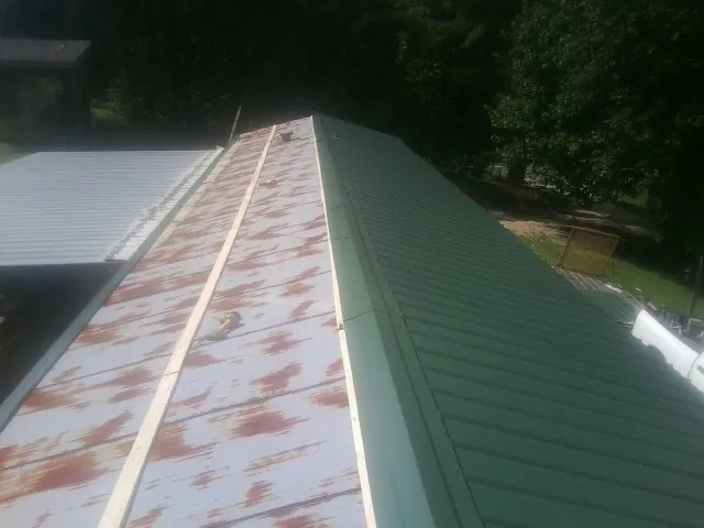 Old rusted panels beside newly installed green metal roofing — Wind Damage Roof Repair by Roofing Brothers in Sicklerville
