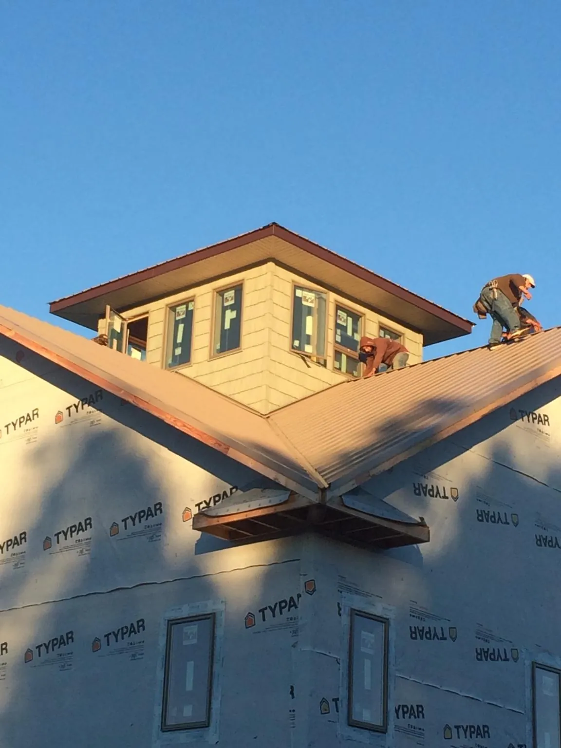 Roofers working around a rooftop cupola on a new metal roof at sunset — Roof Waterproofing in Sicklerville by Roofing Brothers